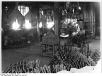 "Aus der Fahrradproduktion Blick in in die alte Fahrradlöterei. Früher wurden die drei Lötstellen am Fahrradrahmen einzeln durch ölgeheizte Öfen gelötet. Der Koll. Heller konstruierte einen Ofen, der in einem Arbeitsgang alle 3 Lötstellen des Rahmens durch Gasflammen in 1 1-2 Minuten lötet. Dieser neue Lötofen wurde im Jahre 1952 entwickelt, er brachte dem Werk eine Einsparung von 36.000 DM" (April 1953)