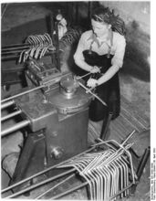 "In der Abteilung Lenkerbiegerei arbeitet die Kollegin Magdalene Paschke an der Rohrbiegemaschine, mit der die Lenker in die richtige Form gebogen werden." (April 1953)
