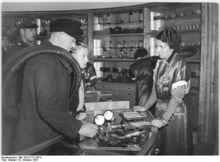 "Am 8.10.1953 eröffnete das Kaufhaus der Handelsorganisation am Alexanderplatz in der Littenstrasse einen Laden für Autos, Motor- und Fahrräder. Auch Ersatzteile sind hier erhältlich. Die Verkäuferin Müller legt Willi Hittelhort Fahrradersatzteile vor." (Oktober 1953)