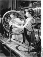 "Auf dem Fließband werden die einzelnen Teile des Rades montiert. -Bei der Montage des Vorderrades.-" (Juli 1956)