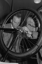 "Zwei Männer betrachten den Zahnkranz am Hinterrad eines Fahrrades." (Herbstmesse 1953)