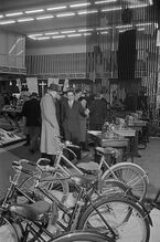 "Messebesucher in der Ausstellungshalle Polens und Ungarns vor einer Präsentation von Fahrrädern und Nähmaschinen." (Frühjahrsmesse 1956)