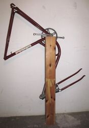 3. Vorbereitung In die zuvor erwähnte Bohrung wird der aus der linken Kurbel ragende Kopf des Kurbelkeils gesteckt und der nach unten hängende Rahmen am Brett fixiert. Hilfreich und lackschonend ist hierbei ein alter Fahrradschlauch; am Steuerkopf sollte eine weiche Zwischenlage verwendet werden. Wie im Bild zu sehen, wird diese Arbeit erheblich vereinfacht, wenn zuvor sämtliche Anbauteile vom Rahmen entfernt werden.