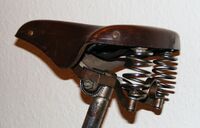 Tourensattel von LLM Zeitraum: 195? - 195?, hier: 1951 Verwendung: alle Fahrradmarken (außer Simson) Decke: Leder, lackiert Gestell: Stahl, verchromt Bemerkungen: schmale Federn, gebogene Querstrebe