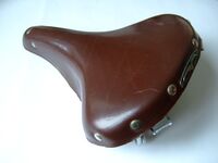 Sportsattel von Möve Zeitraum: um 1955 Verwendung: an Sporträdern oder aus dem Zubehörhandel Lederdecke: dunkelbraun lackiert Gestell: verchromt Bemerkungen: Plakette mit fliegender Möwe, geprägte Linie in den Flanken