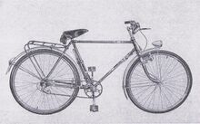 Diese Abbildung des Modells 100 im DHZ-Katalog (1956) zeigt das Fahrrad mit Tourenradpedalen und Scheinwerfer auf dem vorderen Schutzblech. Ebenfalls zu erkennen sind der Kettenfänger und der Kettenleitbolzen. Diese waren bei Verwendung von Kettenschaltungen in Verbindung mit Rücktrittnaben erforderlich.