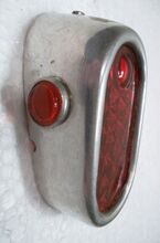 Zeitraum: 1950er Jahre Material: Aluminium, Glas Bekannte Farben: Aluminium (blank) Verwendung: Zubehörteil Bemerkungen: zur Schutzblechmontage; Variante mit roten Seitenfenstern